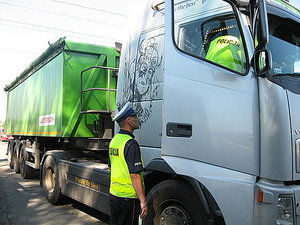 zdjęcie kolorowe: policjanci drogówki kontrolujący samochód ciężarowy