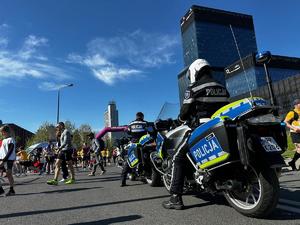 zdjęcie kolorowe: policjant na motorze nadzorujący bezpieczeństwo biegu