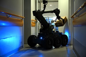 Na zdjęciu widoczny jest robot pirotechniczny wiozący kartonową paczkę