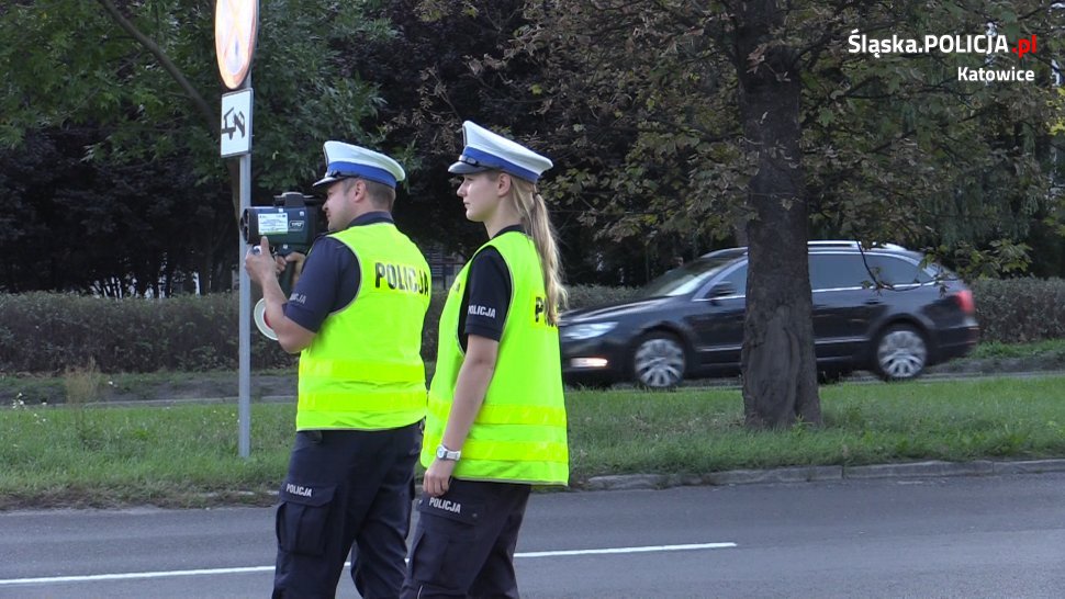 zdjęcie kolorowe: policjant i policjantka z katowickiej drogówki podczas pomiaru prędkości samochodu
