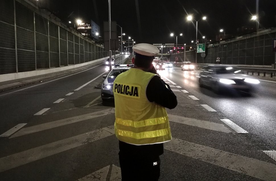 zdjęcie kolorowe: policjant katowickiej drogówki podczas kontroli prędkości pojazdu w ramach działań "Prędkość"