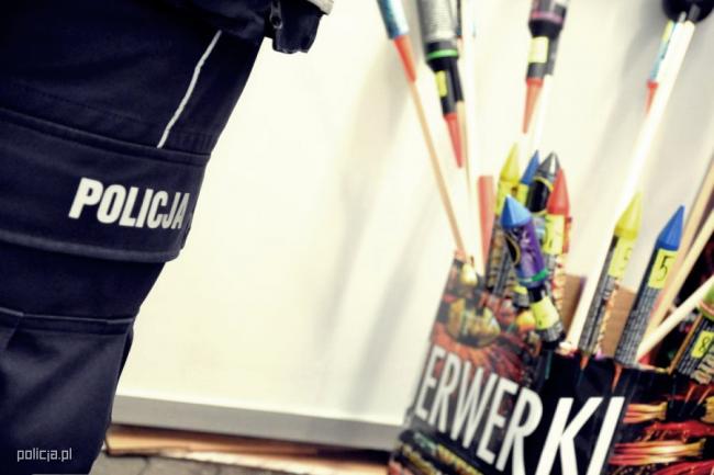 zdjęcie kolorowe: fajerwerki w kartonowym pudle i nogawka spodni służbowych z napisem Policja