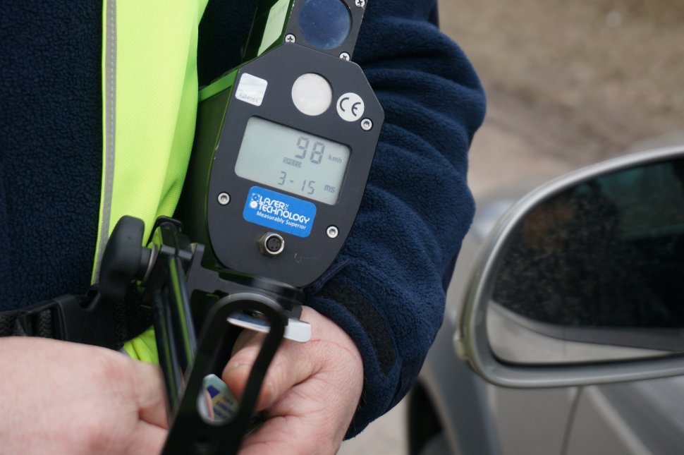 zdjęcie kolorowe: urządzenie do pomiaru prędkości pojazdów trzymane przez policjanta