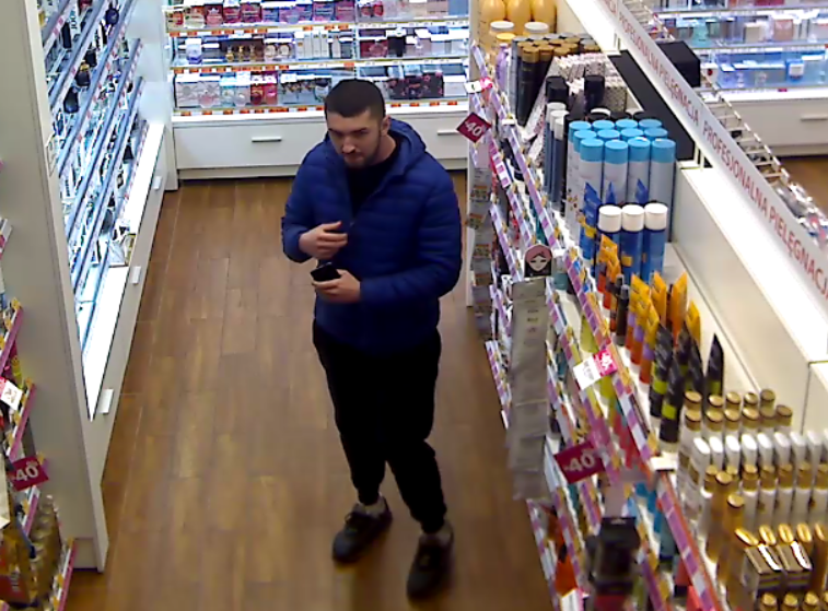 zdjęcie kolorowe: mężczyzna w niebieskiej puchowej kurtce podejrzewany o kradzież perfum w drogerii