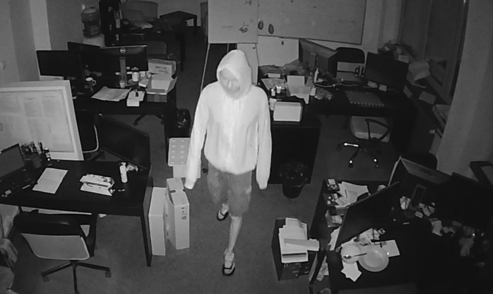 zdjęcie czarno - białe: scereen z monitoringu, który zarejestrował wizerunek mężczyzny podejrzanego o kradzież laptopów, zasilaczy i gotówki z jednej z katowickich firm