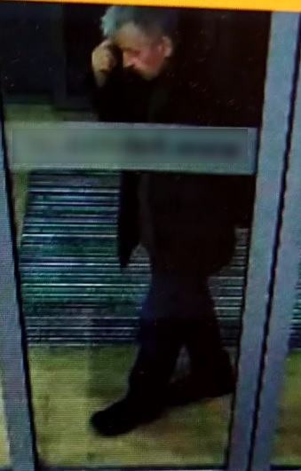 zdjęcie kolorowe: siwy mężczyzna w wieku około 60 lat przy przeszkolonych drzwiach