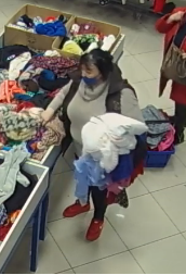 zdjęcie kolorowe: otyła kobieta podejrzewana o kradzież torebki, ubrana w szary długi sweter z golfem, ciemna kamizelkę, ciemne spodnie i czerwone sportowe buty