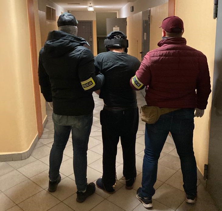 zdjęcie kolorowe: dwóch policjantów wydziału kryminalnego katowickiej komendy na korytarzu  z zatrzymanym mężczyzna podejrzanym o usiłowanie zabójstwa