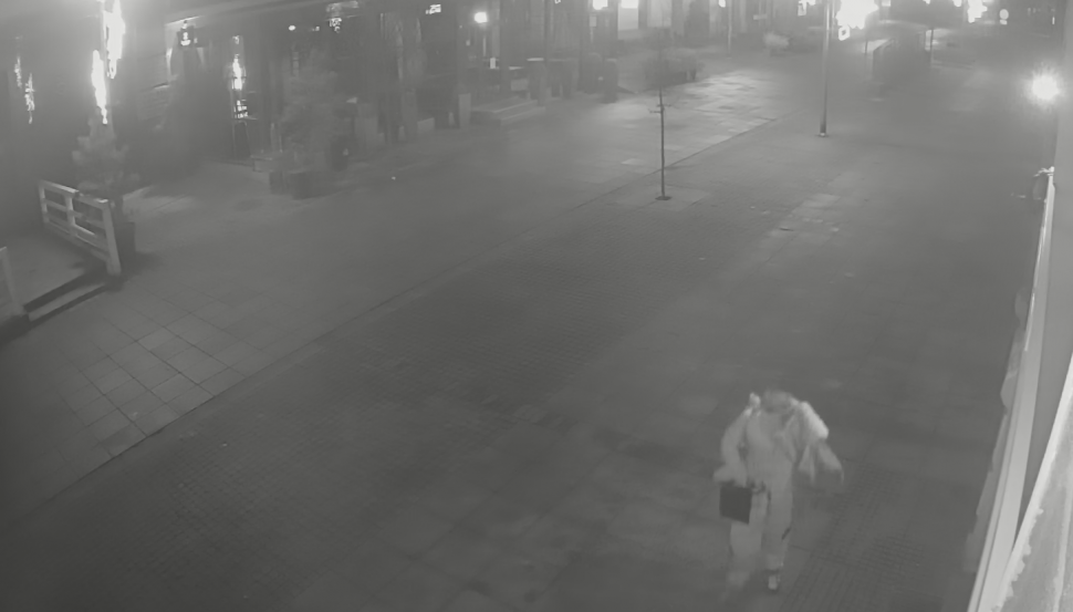 zdjęcie czarno-białe: niewyraźne zdjęcie mężczyzny idącego w nocy chodnikiem