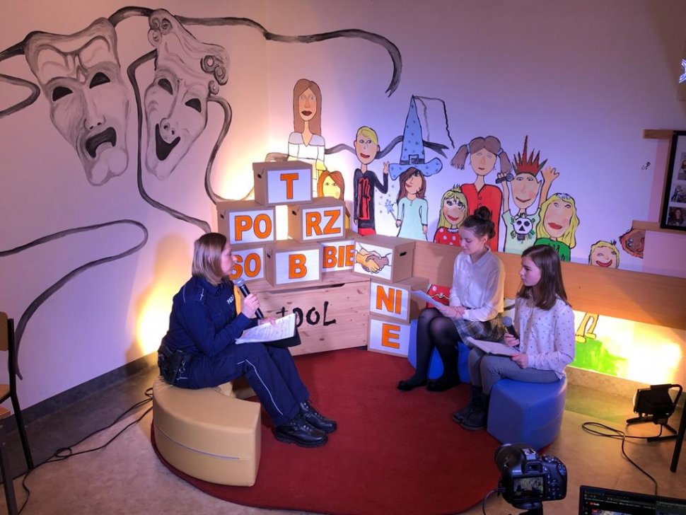 zdjęcie kolorowe: młodsza aspirant Agnieszka Krzysztofik policjantka katowickiej komendy w studio szkolnej telewizji dwiema uczennicami przeprowadzającymi wywiad