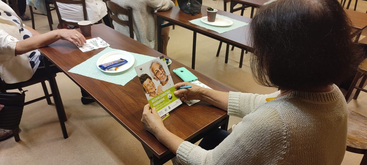 zdjęcie kolorowe: seniorka przeglądająca broszurkę dotycząca bezpieczeństwa