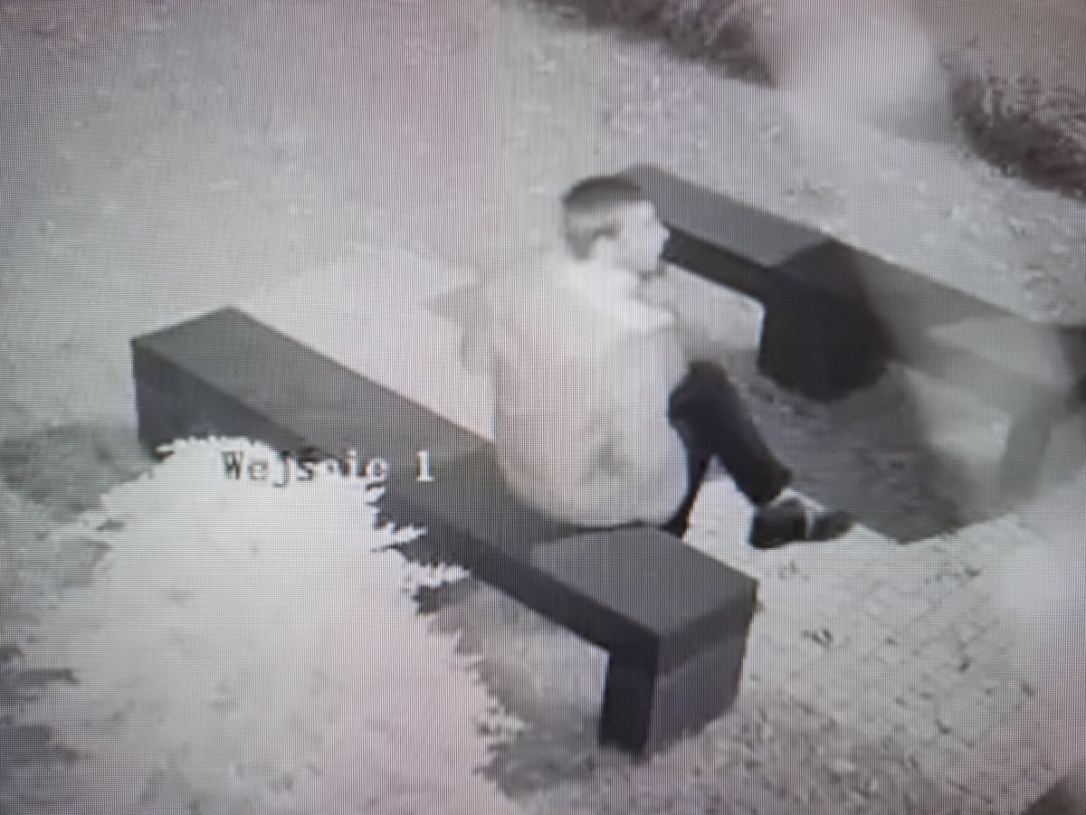 zdjęcie czarno białe: zrzut z monitoringu mężczyzna w kurtce siedzący na ławce