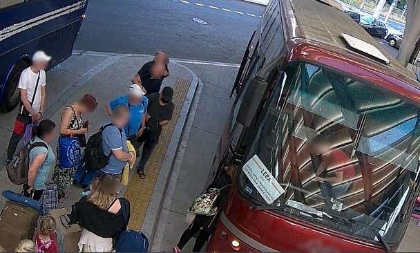 zdjęcie kolorowe: dworzec autobusowy, grupa ludzi oczekująca na peronie przed autobusem i podejrzewany o kradzież kieszonkową mężczyzna ubrany był w ciemnoszarą koszulkę z krótkim rękawem, ciemne spodnie, sandały i czapkę z daszkiem koloru czarnego z załozona czarna maseczka na twarzy