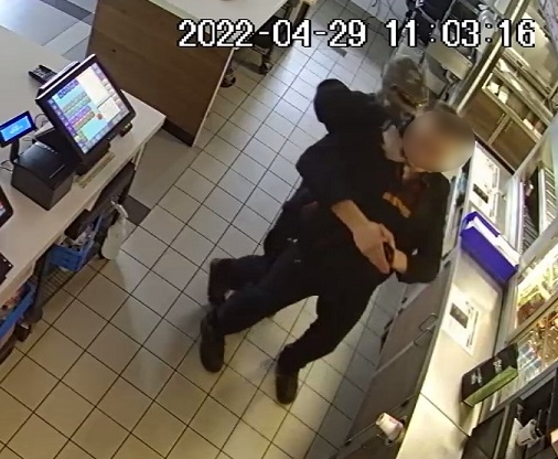 zdjęcie kolorowe: mężczyzna z założoną na twarz komiarką atakuje od tyłu pracownika restauracji