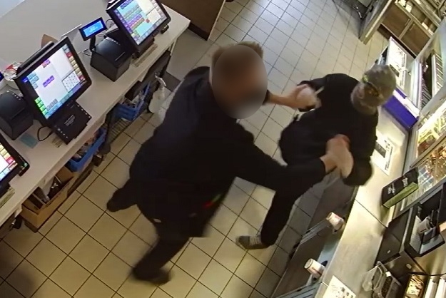 zdjęcie kolorowe: mężczyzna z założoną na twarz komiarką atakuje od tyłu pracownika restauracji, który broni się przed atakiem