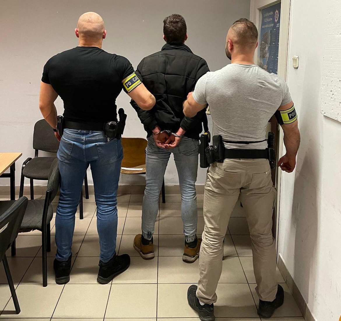 zdjęcie kolorowe: dwóch policjantów katowickiego oddziału prewencji z zatrzymanym mężczyzną, który był poszukiwany listem gończym