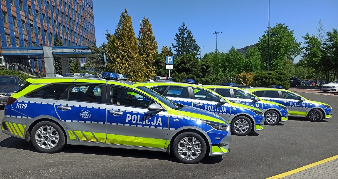 zdjęcie kolorowe: 4 oznakowane policyjne radiowozy ustawione na parkingu przed katowicką komendą