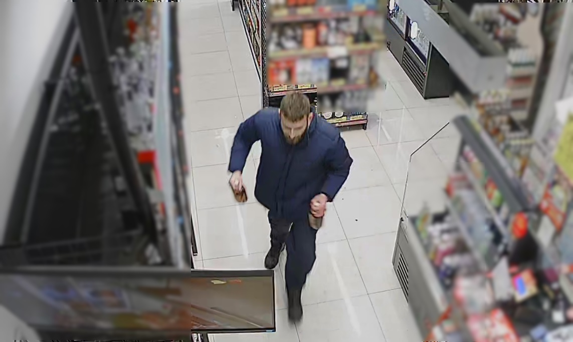 zdjęcie kolorowe: mężczyzna w sklepie który zabrał alkohol z półki