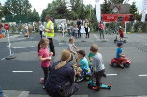 Dzieci bawiące się z policjantką w miasteczku ruchu drogowego