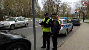 Policjant ze strażniczką miejską stoją obok kontrolowanego samochodu z tyłu stoi radiowóz.