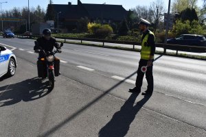 policjant podchodzi do zatrzymanego do kontroli motorowerzysty