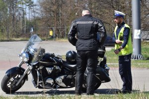policjant stoi obok motocyklisty a przed nimi stoi motocykl