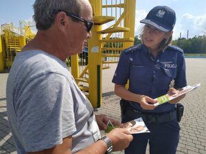 Zdjęcie kolorowe: policjantka katowickiej komendy podczas rozmowy ze starszą osoba o bezpieczeństwie i zasadach postępowania z oszustami