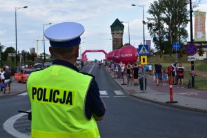 na zdjęciu widać policjanta zabezpieczającego trasę wyścigu przednim widoczna jest ulica i budynki Muzeum Śląskiego