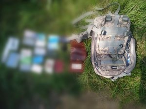 Na zdjęciu widać plecak leżący na trawie obok niego leżą portfel oraz dokumenty