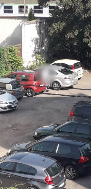 Na zdjęciu widać sprawcę włamania jak wychodzi za samochodu na parkingu na którym zaparkowane są inne samochody