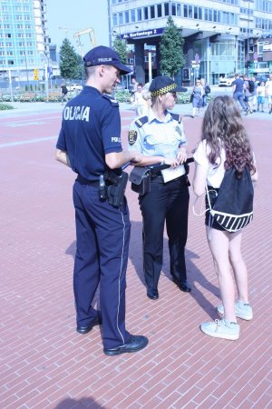 Na zdjęciu widać policjanta i strażnika miejskiego obok stoi młoda dziewczyna