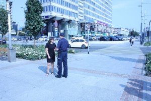 Na zdjęciu widać policjanta obok stoi kobieta w tle widać przejście dla pieszych