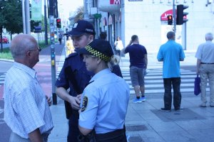 Na zdjęciu widać policjanta i strażnika miejskiego obok stoi straszy mężczyzna w tel widać przejście dla pieszych