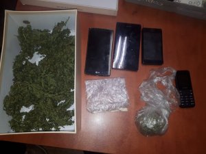 zdjęcie kolorowe: zabezpieczone przez policjantów pudełko z marihuaną, woreczek z marihuaną, amfetamina i telefony komórkowe
