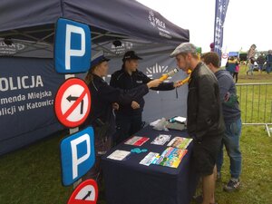 zdjęcie kolorowe: policjanci katowickiej komendy podczas  Summer Cars Party on Fire 2019  na katowickim Lotnisku Muchowiec z uczestnikami zlotu motoryzacyjnego