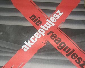 zdjęcie kolorowe: plakat promujący akcję "Nie reagujesz - akceptujesz", twarz człowieka spoglądająca przez żaluzje