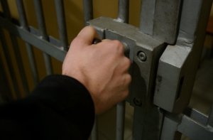 zdjęcie kolorowe: dłoń zaciśnięta na kluczu z zamka drzwi  do aresztu