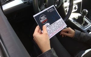 zdjęcie kolorowe: policjant katowickiej komendy podczas przekazania ulotki dla kierującego w ramach projektu „Twoje Światła - Twoje Bezpieczeństwo!”