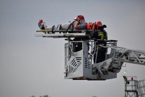 zdjęcie kolorowe: transport rannego spadochroniarza drabiną strażacką