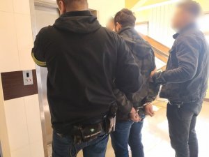 zdjęcie kolorowe: policjanci katowickiej komendy z mężczyzną podejrzanym o oszustwa
