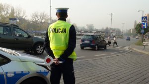 zdjęcie kolorowe: policjant drogówki podczas policyjnych działań w rejonie oznakowanego przejścia dla pieszych