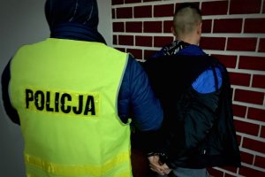 Na kolorowym zdjeciu widać policjanta i osobę zatrzymaną przy śaccianie