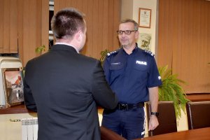 Na kolorowym zdjęciu widac mężczyznę ubranego w czarną marynarkę oraz Komendanta Miejskiego Policji w Katowicach jak stoją w gabinecie komendanta