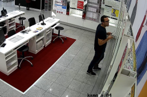 zdjęcie kolorowe: mężczyzna podejrzewany o kradzież oprawek okularów w salonie optycznym, zarejestrowany przez sklepowy monitoring
