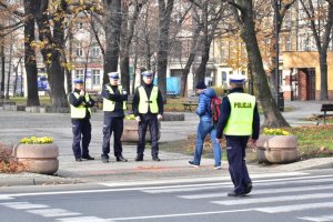 Na zdjęciu widać napis odłóż telefon i żyj naniesiony na przejście dla pieszych obok stoi trzech policjantów a przez przejście idzie pieszy i policjant