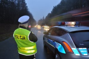 zdjęcie kolorowe: policjantka ruchu drogowego podczas kontroli prędkości pojazdów