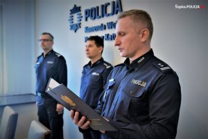Na zdjęciu widać trzech oficerów policji stojących w sali odpraw Komendy Wojewódzkiej Policji w Katowicach