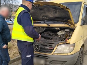 zdjęcie kolorowe: policjant katowickiej drogówki podczas działań "Smog" sprawdza stan techniczny zatrzymanego do kontroli pojazdu