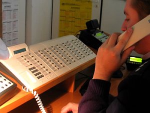 zdjęcie kolorowe: policjant rozmawiający przez telefon stacjonarny