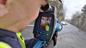 zdjęcie kolorowe: policjant ruchu drogowego podczas kontroli prędkości pojazdów